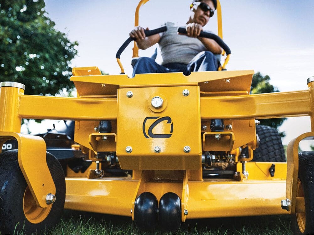 A man confidently drives a yellow 2025 Cub Cadet® PRO Z 960 L zero-turn mower across a lush green lawn.